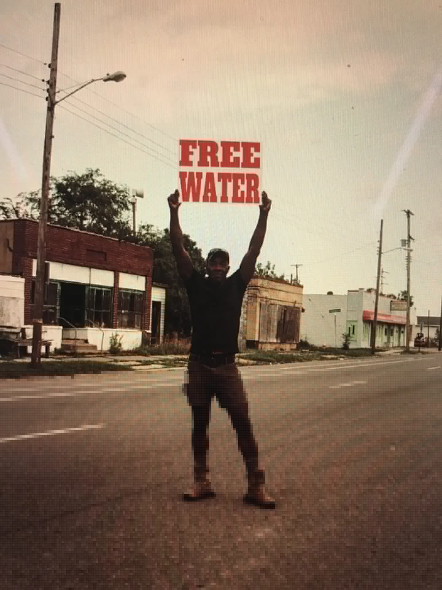 Moses West holding a Free Water sign in Flint, Michigan
